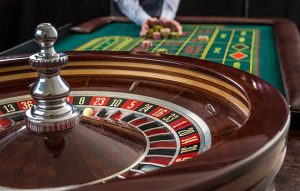 Roulette and piles of gambling chips on a green table in casino.  Man hand over casino chips  - bet.